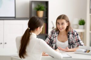 Young female psychologist working with teenager girl in office.