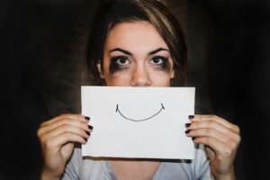 Sad woman holding paper with a smile Photo by Sydney Sims on Unsplash